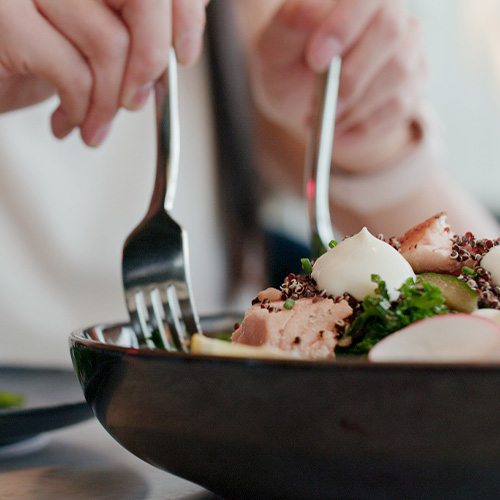 Hands scooping healthy salad onto their plate with forks