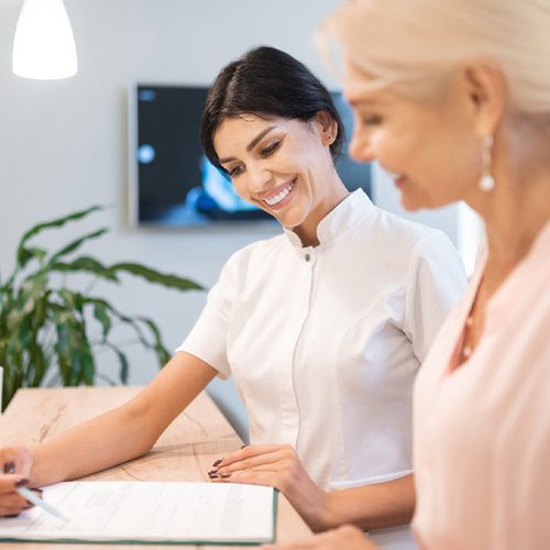 Smiling dental assistant showing patient forms
