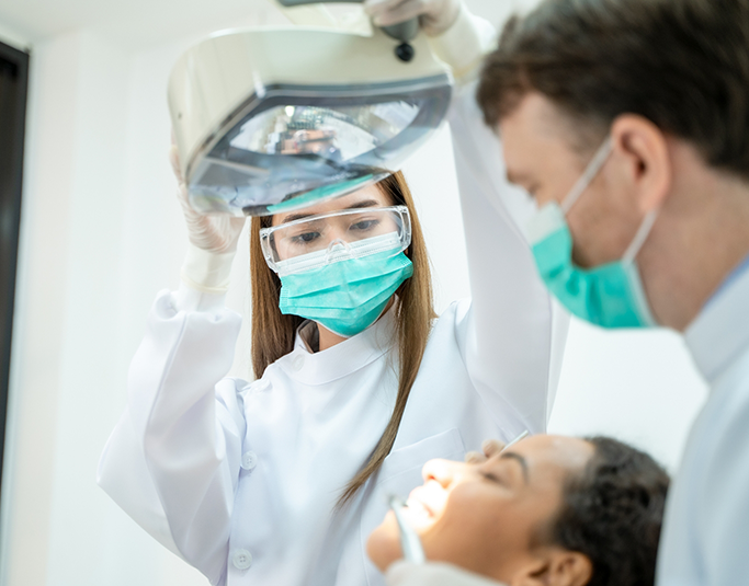 Dentist and assistant preparing to treat a patient