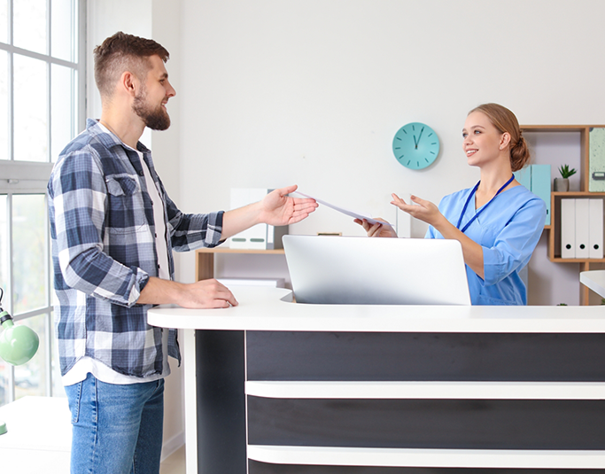 Dental team member handing paperwork to a patient at the front desk