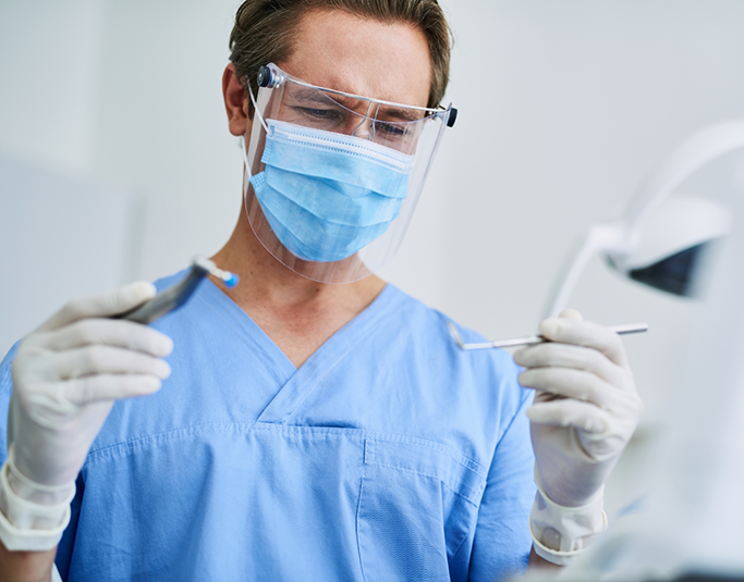 Dentist wearing a face mask and face shield while treating a patient