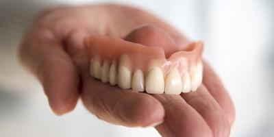 Holding dentures in Windermere, FL in palm of hand