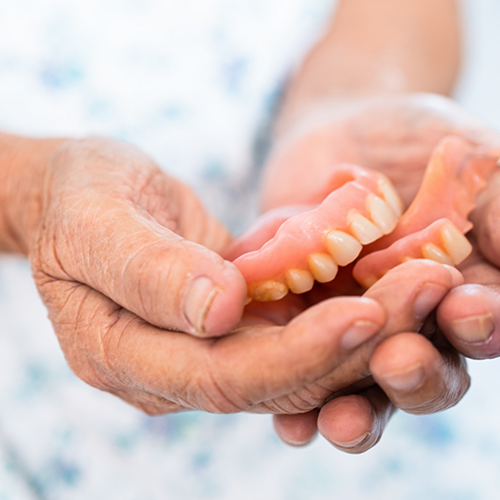 Person holding a set of full dentures in their hands