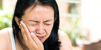 woman holding mouth in pain 