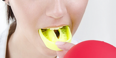 close up person putting in yellow mouthguard 