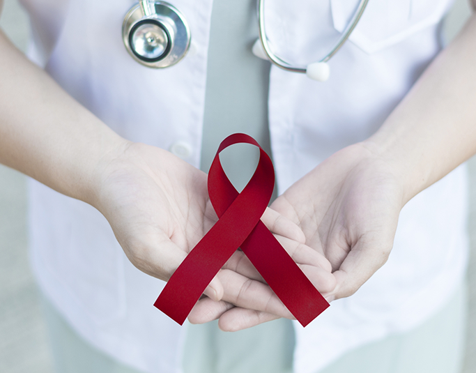 Dentist holding a red ribbon for oral cancer awareness