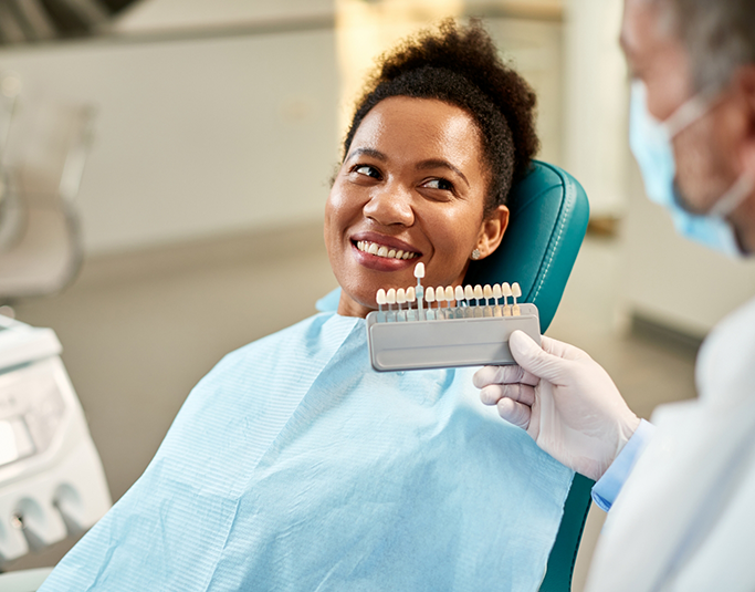 Windermere cosmetic dentist holding a veneer shade guide in front of a patient's teeth