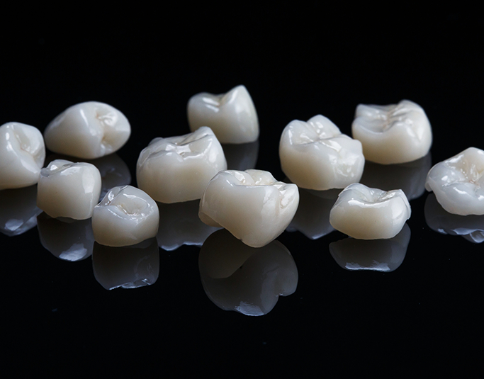 Several white dental crowns against a black background