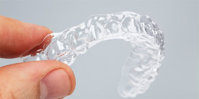 A person holding a clear aligner.