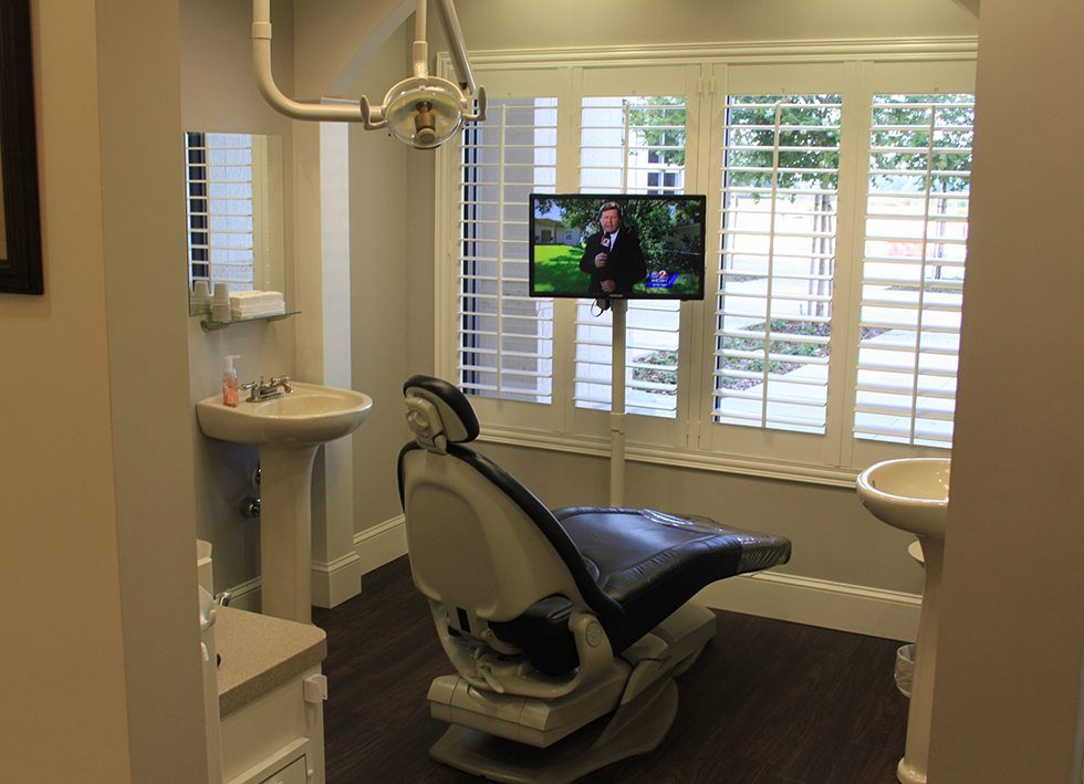 Dental treatment room with a TV mounted in front of the window