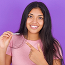 Smiling young woman holding an Invisalign clear aligner