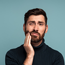 Man holding his cheek and wincing in pain