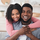 Young man and woman smiling and hugging at home