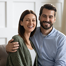 Smiling man and woman sitting on their couch