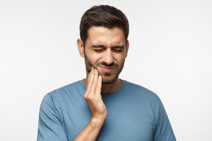 Man in blue shirt with jaw pain on one side