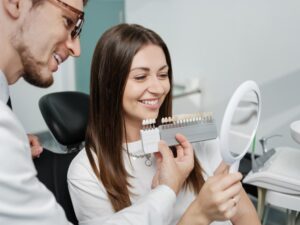 Patient looking at veneers in dentist's chair.