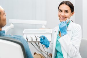 Dentist pulling down mask and smiling during work.