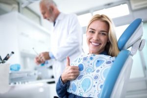 woman at dentist's office giving thumbs up.