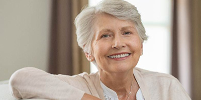 Senior woman with dentures in Windermere, FL resting on couch