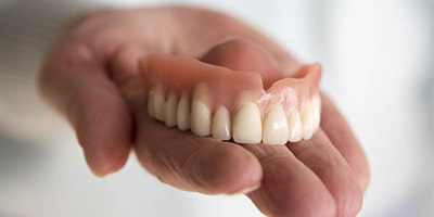 Holding dentures in Windermere, FL in palm of hand