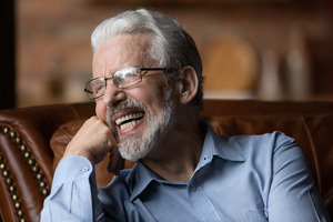 Senior man on couch smiling with dentures