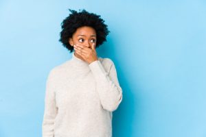 person with gingivitis covering mouth